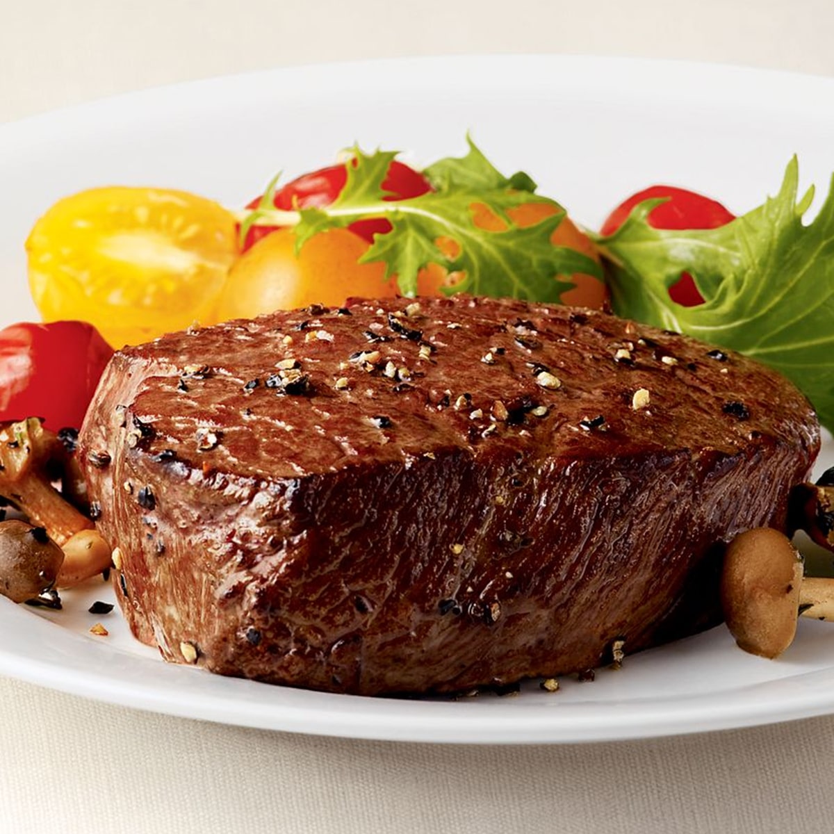 Perfectly seared filet steak served with fresh salad greens and colourful cherry tomatoes on a white plate served at Mahony’s Steak House Bishopbriggs.
